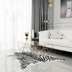 Modern rectangular coffee table with gold geometric base on black and white striped rug