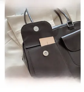 Detail der dunkelbraunen PU-Ledertasche mit zwei Pattentaschen und silbernen Schnallen