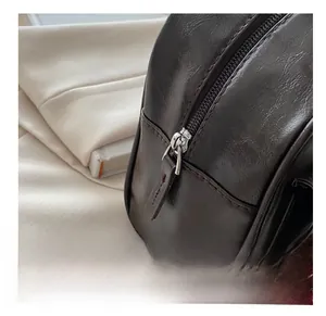 Detailaufnahme des glatten Metallreißverschlusses an dunkelbrauner Lederhandtasche