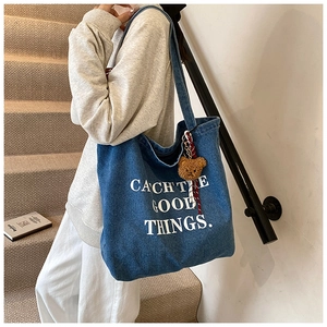 Dettaglio della borsa tote in denim blu con scritta Catch The Good Things e ciondolo