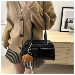 Detail der schwarzen Vintage-Schultertasche mit Fronttaschen und braunem Plüschanhänger