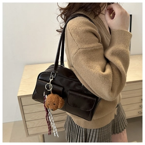 Detail der dunkelbraunen Vintage-Schultertasche mit zwei Vordertaschen und Bärenanhänger