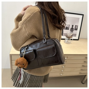Detail der braunen Vintage-Tasche mit Doppeltaschen und süßem Plüsch-Hundeanhänger