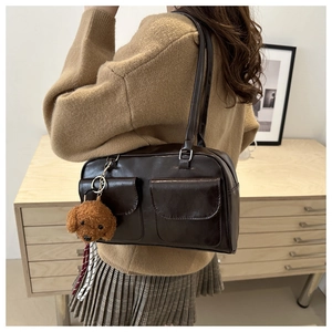 Braune Vintage-Schultertasche mit Plüsch-Hundeanhänger und Taschendetails auf der Seite
