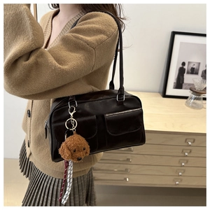 Detaillierte Seitenansicht einer braunen Vintage-Schultertasche mit Teddy-Anhänger