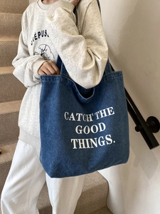 Borsa tote in denim blu con testo bianco CATCH THE GOOD THINGS in un contesto lifestyle