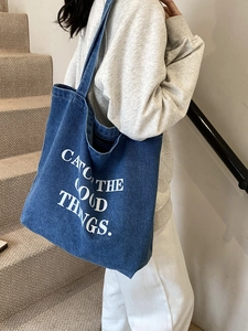 Grande borsa tote in denim blu scuro con stampa Catch The Good Things indossata da modella