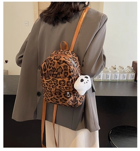 Détail d'un mini sac à dos imprimé léopard avec bretelles brunes et porte-clés peluche