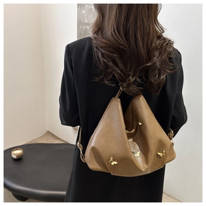 Brown leather backpack with golden butterfly charms shown on a model's back