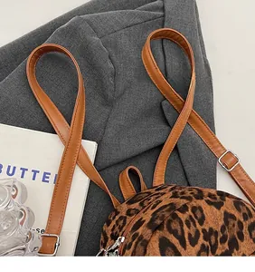 Detail of leopard print backpack with brown leather strap and silver metal hardware buckle