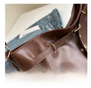 Detailed close-up of premium brown leather stitching and gold hardware buckle on a tote bag