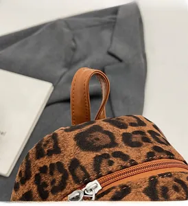 Detail of leopard print plush fabric and brown faux leather handle with silver zipper