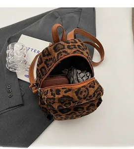 Detail view showing large interior capacity of leopard print backpack with brown leather strap