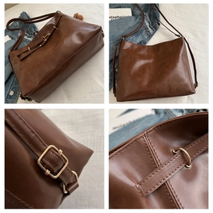 Detailed view of brown matte leather tote stitching and gold hardware with bear charm