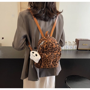 Gros plan d'un mini sac à dos à imprimé léopard avec lanières en cuir et porte-clés panda
