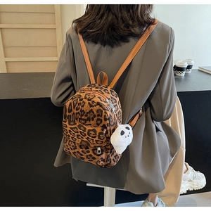 Mini sac à dos imprimé léopard avec charm panda en peluche blanche porté par un mannequin
