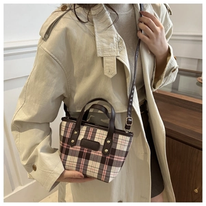 Détail du sac à main à carreaux roses avec bandoulière sur un modèle en trench-coat