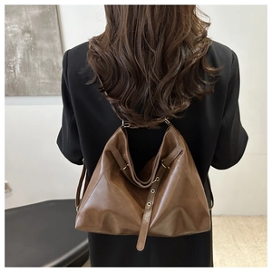 Detail of dark brown leather tote bag showing vintage texture and metal eyelet strap