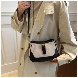 Close-up of minimalist canvas and leather shoulder bag styled with a beige trench coat