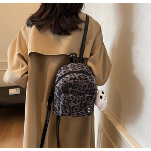 Mini leopard print backpack with white ghost charm shown on model in khaki trench coat