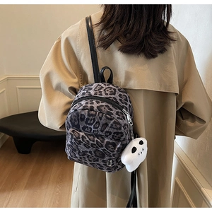 Mini sac à dos imprimé léopard porté par un mannequin avec charm en peluche et fermeture
