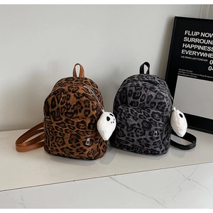 Fashionable leopard print mini backpack with plush ghost charm on a white surface