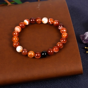 Natural red agate beaded bracelet featuring obsidian accents on premium leather display