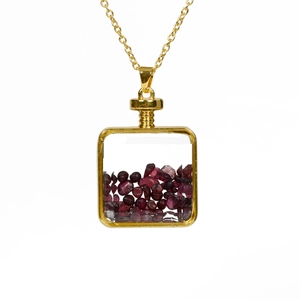 Gold chain necklace featuring a transparent square pendant filled with red crushed stones