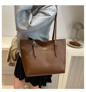 Close-up of large brown tote bag with metal buckle and gold fashion logo detail