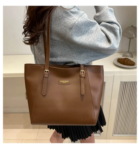 Detail view of a large brown leather tote bag with elegant golden embossed logo text