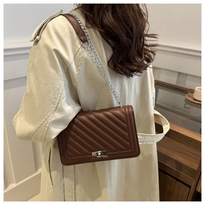 Detail of dark brown quilted leather crossbody bag with silver metal chain strap