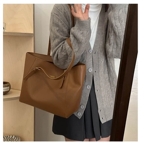Detailed view of a classic brown tote bag with premium leather texture and gold logo plate