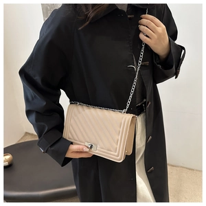 Detail of beige V-quilted leather bag with silver chain strap and metal turn-lock