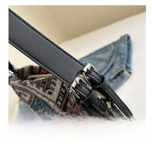 Detail of adjustable black leather strap with silver buckle on canvas bucket bag