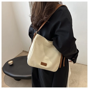 Detailed close-up of a canvas hobo bag with brown leather strap and logo patch