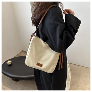 Detail of off-white canvas bucket bag with brown leather strap and brand label
