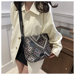 Detail of colorful geometric woven canvas crossbody bag with ethnic patterns and black strap
