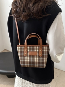 Petit sac à main chic à carreaux marron et bleu avec bandoulière porté par un mannequin