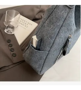 Close-up of grey-blue textured tote bag showing side pocket and metal zipper details