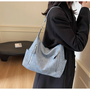 Detail of light blue hobo bag with side silver zippers and matte texture on shoulder