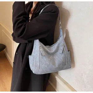 Large light blue hobo tote bag in matte suede leather with silver zippers shown on shoulder