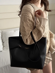 Minimalist large black leather tote bag for women shown as stylish shoulder bag on model