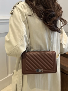 Quilted dark brown leather crossbody bag with silver chain strap shown on a model