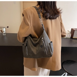 Detail of dark grey vintage tote bag with twin front zippers shown on a model