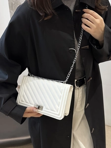 White quilted crossbody bag with silver chain strap and metal lock shown on a model