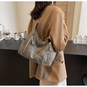 Detail of vintage gray textured tote bag with multiple zippers and wide strap on model
