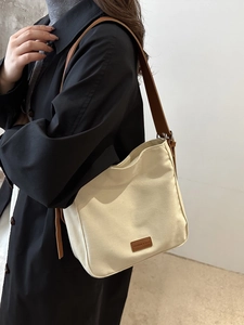 Chic beige canvas bucket bag with brown leather straps and fashion label decoration
