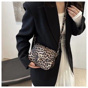 Detail der Satteltasche mit Leopardenmuster und goldener Hufeisenschnalle auf schwarzem Blazer