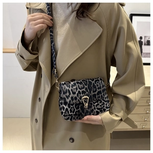 Detail der modischen Leopard-Umhängetasche mit goldener Schließe am beigen Trenchcoat