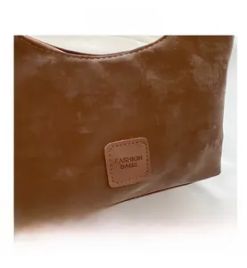 Close-up of the brown faux suede dumpling bag with a stitched Fashion Bags label